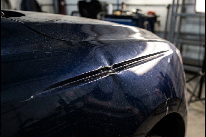 Crease dent across a navy fender