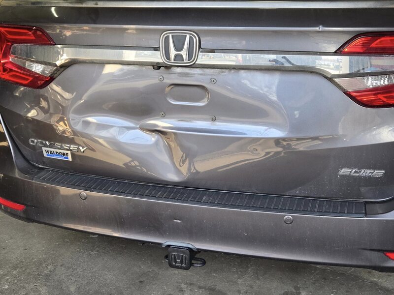 Deep dent in a Honda Odyssey tailgate before repair