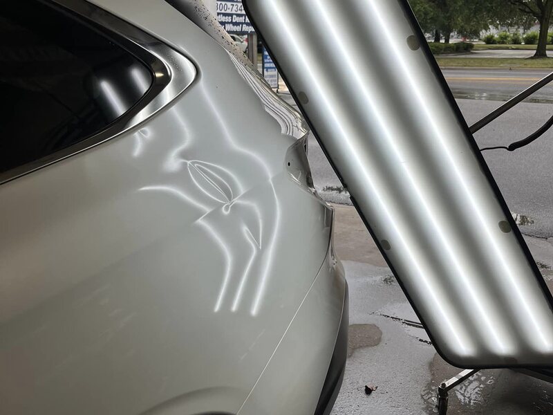 Deep crease dent in a white SUV quarter panel before PDR